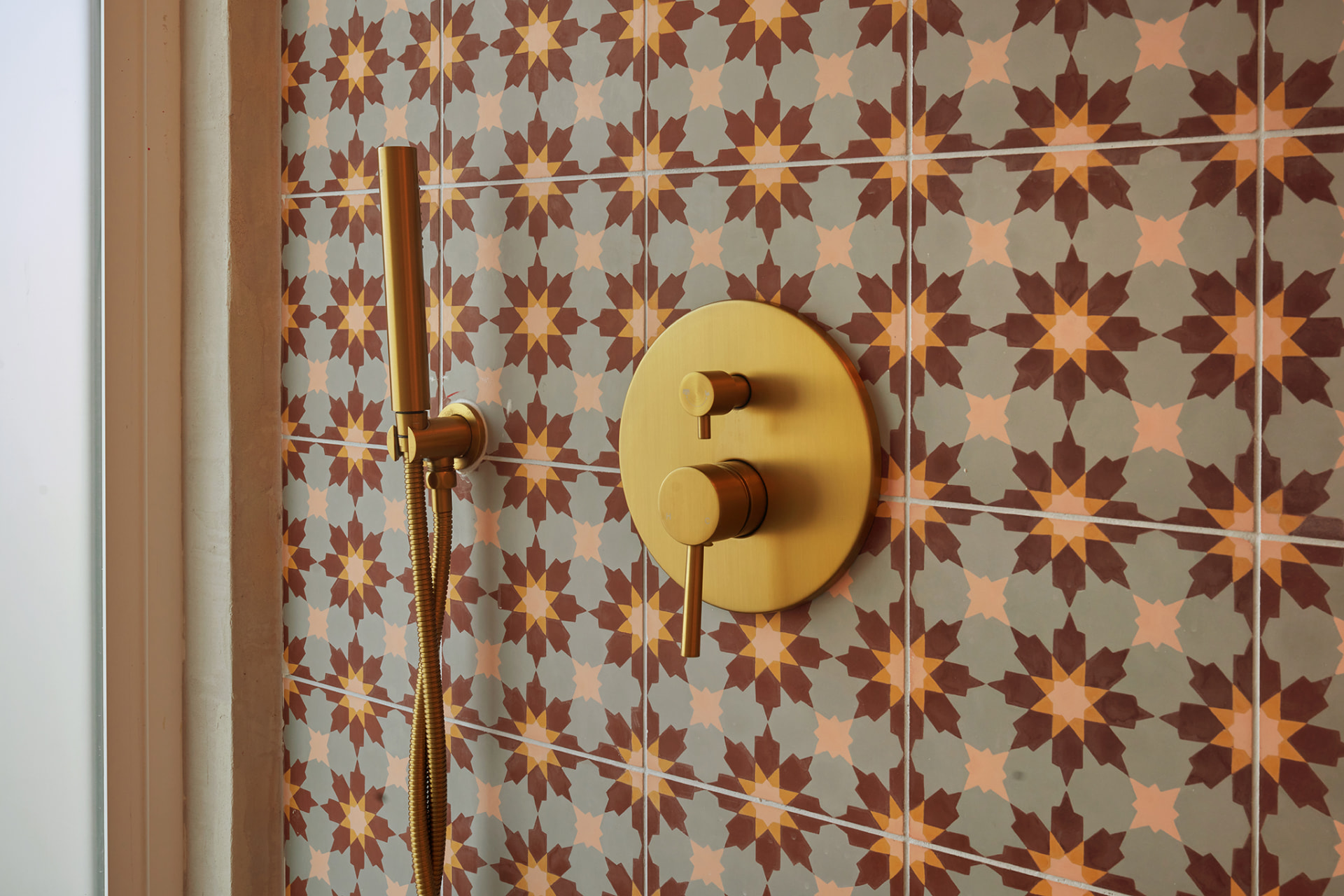 Shower with patterned cement star tile and brass fixtures